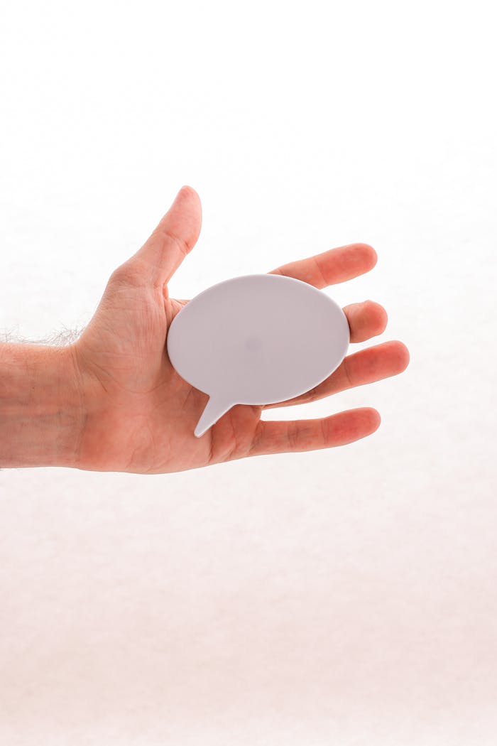 Closeup of a hand holding a blank speech bubble sign, ideal for creative concepts and mockups.
